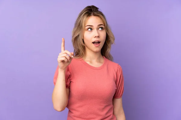 十代のロシアの女の子は指を持ち上げながら解決策を実現しようと紫色の背景に隔離されました — ストック写真