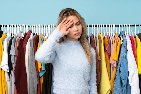Teenager Russian girl buying some clothes isolated on blue background with tired and sick expression