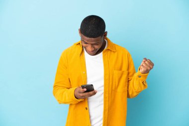 Mavi arka plandaki genç latin adam şaşırdı ve bir mesaj gönderiyor.