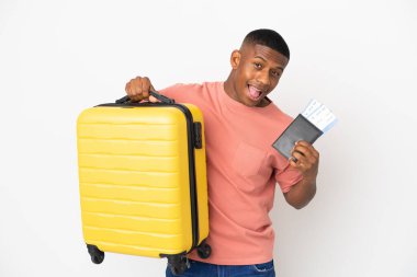Beyaz arka planda izole edilmiş genç Latin bir adam, tatilde bavul ve pasaportla.
