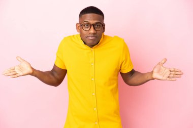 Pembe arka planda izole edilmiş genç Latin adam ellerini kaldırırken şüpheye düşüyor.