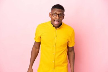 Pembe arka planda yalıtılmış genç latin adam, şaşırmış yüz ifadesi.