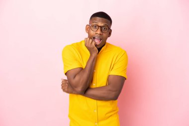 Pembe arka planda izole edilmiş genç Latin adam şaşırmış ve şaşırmış görünüyor.