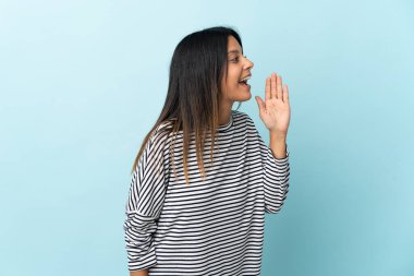 Mavi arka planda izole edilmiş beyaz kız ağzı sonuna kadar açık bağırıyor.