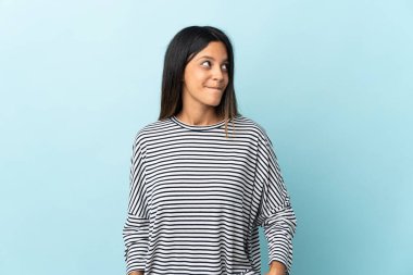 Kafkas kızı mavi arka planda izole edilmiş, yukarı bakarken şüpheleri var.