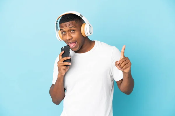 Jeune Homme Latin Isolé Sur Fond Bleu Écoutant Musique Avec — Photo