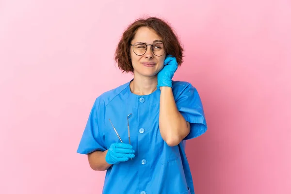 女性英語歯科医保持ツール上の隔離された上のピンクの背景不満とカバー耳 — ストック写真