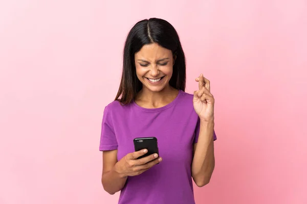 핸드폰을 사용하여 분홍색 배경으로 고립된 손가락을 교차시키는 — 스톡 사진