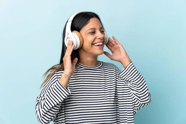 Beyaz kız mavi arka planda izole edilmiş müzik dinliyor ve şarkı söylüyor.