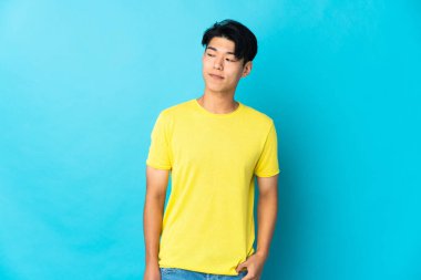 Young Chinese man isolated on blue background having doubts while looking side
