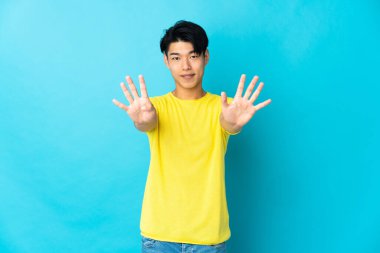 Young Chinese man isolated on blue background counting nine with fingers