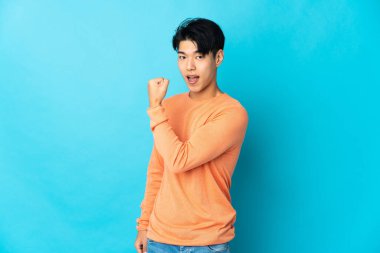 Mavi arka planda izole edilmiş genç bir Çinli zaferi kutluyor.