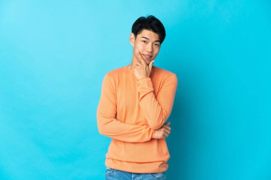 Young Chinese man isolated on blue background happy and smiling