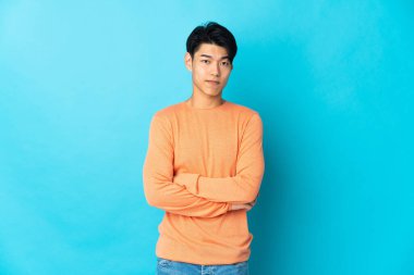 Young Chinese man isolated on blue background feeling upset
