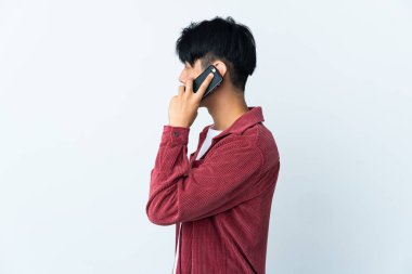 Beyaz arka planda izole edilmiş genç bir Çinli cep telefonuyla sohbet ediyor.