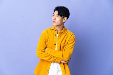 Mor arka planda izole edilmiş genç bir Çinli yan tarafa bakıyor.