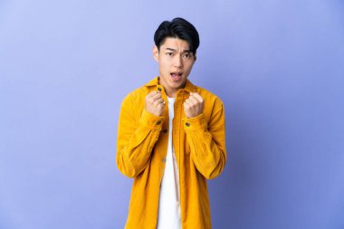 Young Chinese man isolated on purple background frustrated by a bad situation