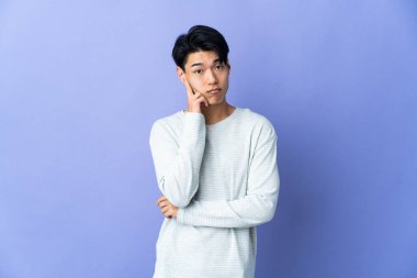 Mor arka planda izole edilmiş genç Çinli bir adam bir fikir düşünüyor.