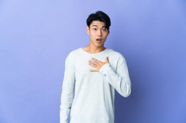 Mor arka planda izole edilmiş genç bir Çinli sağa bakarken şaşırmış ve şok olmuştu.