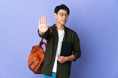 Mor arka planda izole edilmiş genç bir bayan dur hareketi yapıyor ve hayal kırıklığına uğruyor.