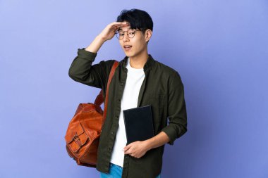 Mor arka planda izole edilmiş genç bir bayan yan tarafa bakarken sürpriz jest yapıyor.