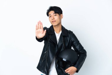 Chinese man with a motorcycle helmet isolated on white background making stop gesture