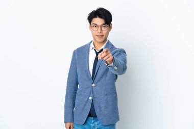 Genç Çinli iş adamı beyaz arka planda izole edilmiş mutlu bir ifadeyle ön tarafı işaret ediyor.