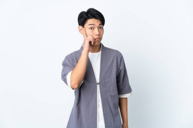 Genç Çinli bir adam beyaz arka planda izole edilmiş bir fikir düşünüyor.