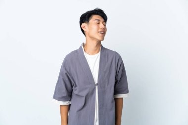 Genç Çinli bir adam beyaz arka planda yalnız gülüyor.