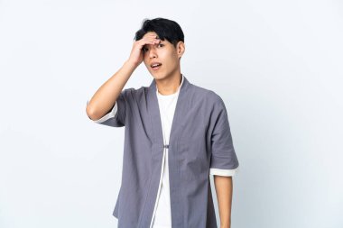 Young Chinese man isolated on white background doing surprise gesture while looking to the side