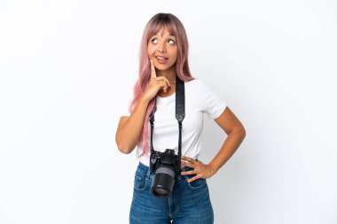 Young photographer mixed race woman with pink hair isolated on white background thinking an idea while looking up