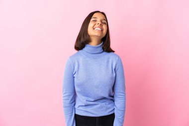 Genç Latin kadın pembe arka planda izole edilmiş gülüyor.