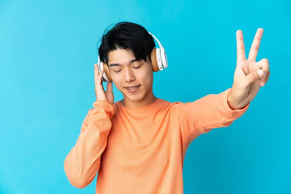 Joven Chino Aislado Sobre Fondo Azul Escuchando Música Cantando — Foto de Stock