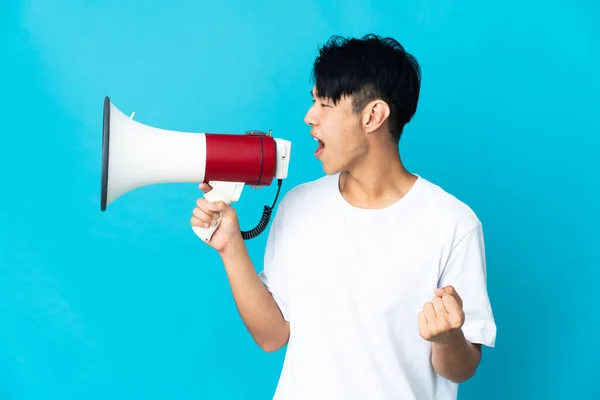 Jonge Chinese Man Geïsoleerd Blauwe Achtergrond Schreeuwen Door Een Megafoon — Stockfoto