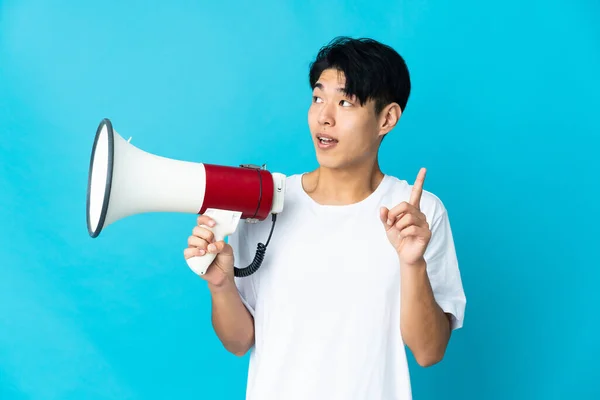 Young Chinese Man Isolated Blue Background Holding Megaphone Intending Realizes — стокове фото