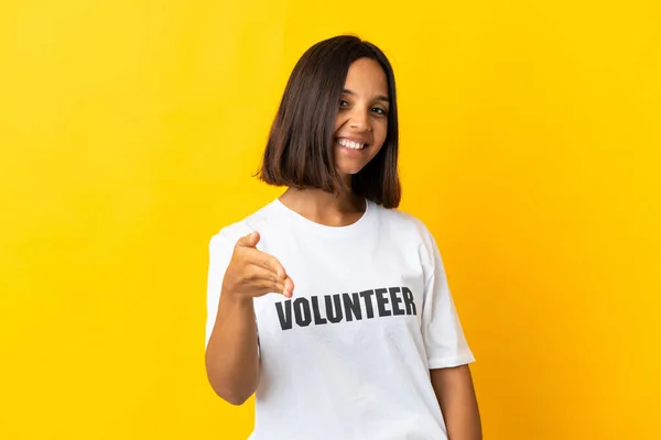 Young Volunteer Woman Isolated Yellow Background Shaking Hands Closing Good — Foto de Stock