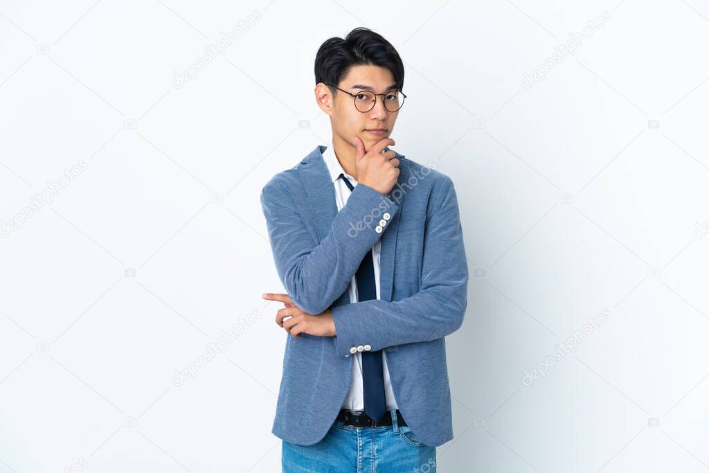 Young Chinese business man isolated on white background having doubts and thinking