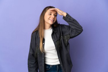 Genç Litvanyalı kadın, mor arka planda izole edilmiş. Bir şeye bakmak için uzaklara bakıyor.