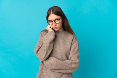 Genç Litvanyalı kadın mavi arka planda izole edilmiş, yorgun ve sıkılmış bir ifadeyle.