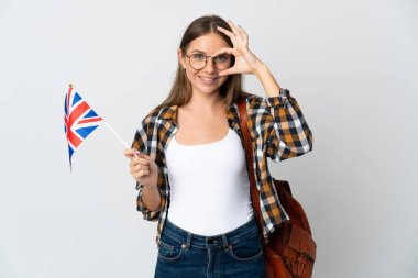 Birleşik Krallık bayrağını tutan genç Litvanyalı kadın beyaz arka planda izole edilmiş, parmaklarıyla işaret veriyor.
