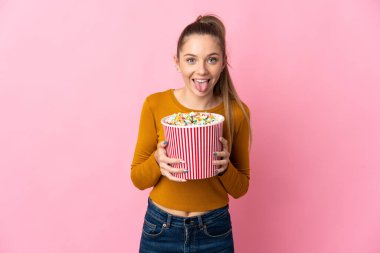 Genç Litvanyalı bir kadın pembe arka planda izole edilmiş. Elinde koca bir kova patlamış mısır var.