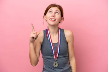 Pembe arka planda izole edilmiş madalyalı genç bir İngiliz kadın.