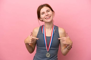 Pembe arka planda madalyalı genç bir İngiliz kadını gururlu ve kendini beğenmiş.