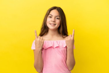 Sarı arka planda izole edilmiş küçük beyaz kız harika bir fikre işaret ediyor.