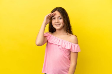 Sarı arka planda izole edilmiş küçük beyaz kız mutlu bir ifadeyle selamlıyor.