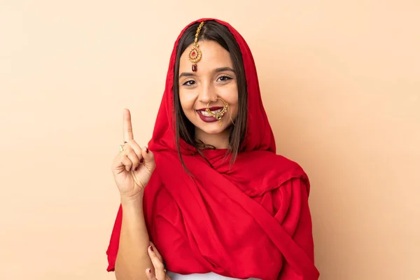 Mladá Indická Žena Izolované Béžové Pozadí Ukazující Zvedající Prst Znamení — Stock fotografie