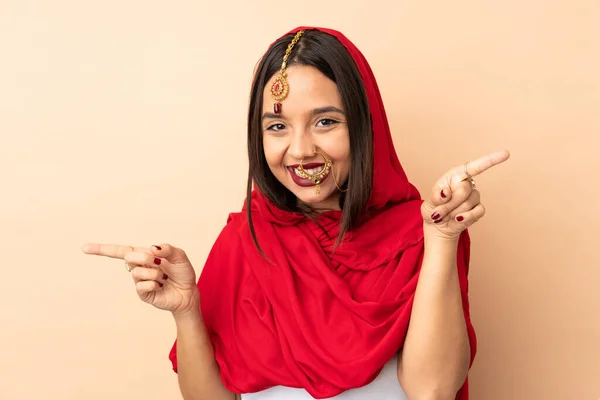 Jonge Indiaanse Vrouw Geïsoleerd Beige Achtergrond Wijzend Vinger Naar Lateralen — Stockfoto