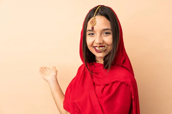Młoda Hinduska Kobieta Odizolowana Beżowym Tle Wyciąga Ręce Bok Zaproszenie — Zdjęcie stockowe