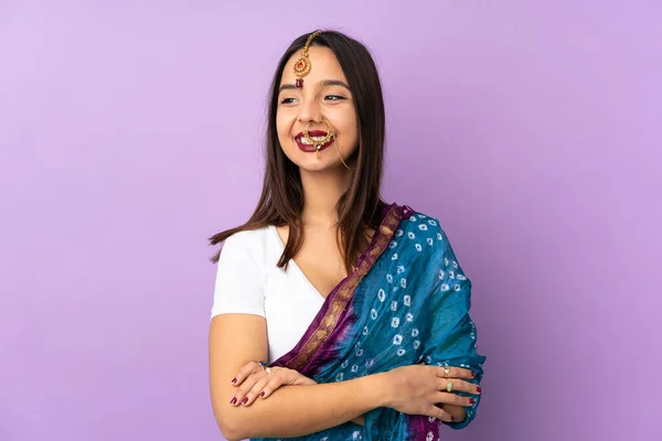 若いインド人女性は 側を見て 笑みを浮かべて紫色の背景に隔離 — ストック写真