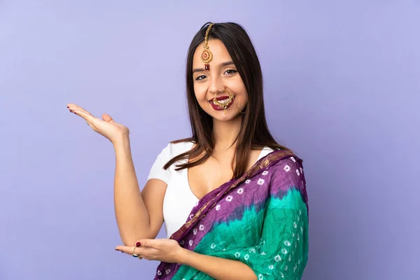 年轻的印度妇女被隔离在紫色背景下 向旁边伸出手来 感谢她邀请我们来 — 图库照片